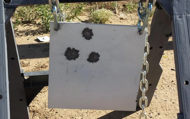 Steel target with three bullet impacts