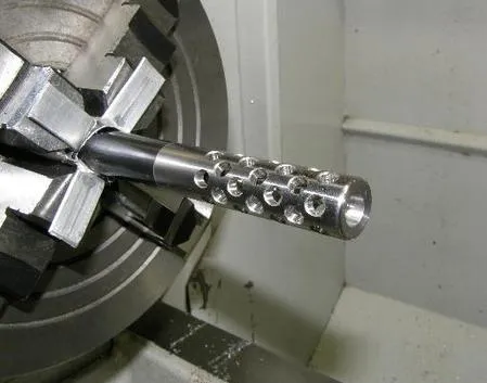 Muzzle brake held in a lathe chuck after boring and polishing